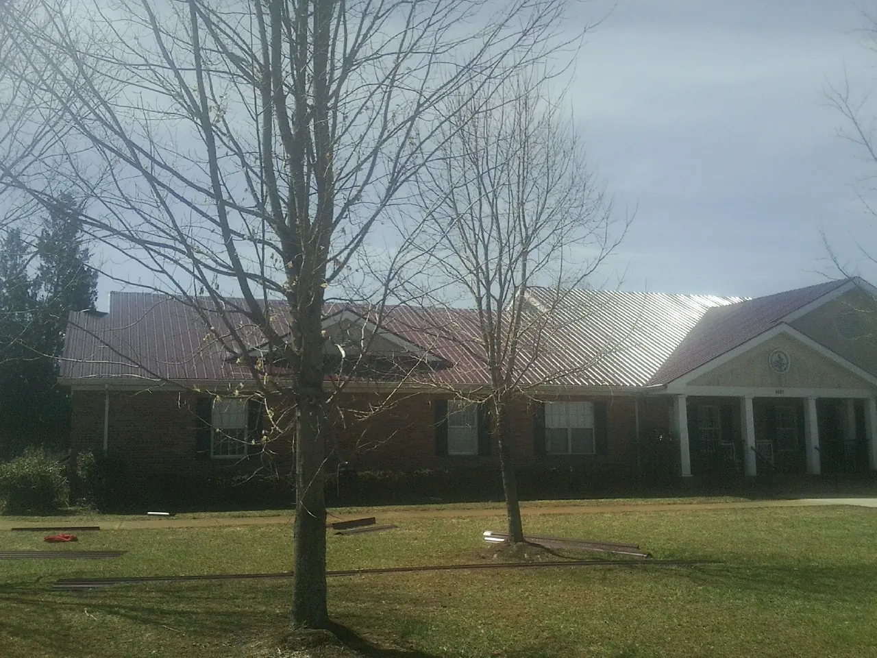 Red metal roof on a brick building seen from the front lawn in Granville